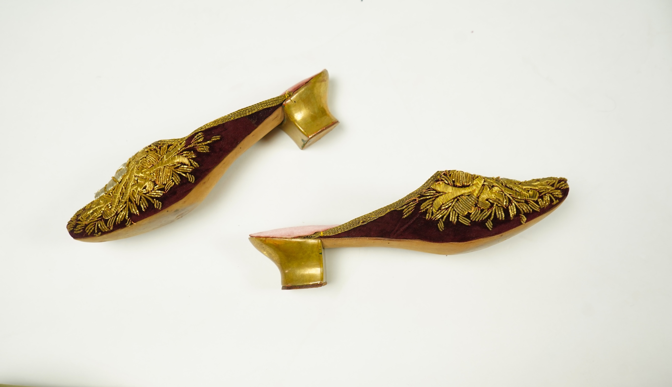 An unusual pair of Edwardian ladies red velvet and gold embroidered mules, a pair of 19th century ladies cream silk shoes and a pair of baby's embroidered suede shoes. Mules stamped 41at toe of sole. Condition - all thre